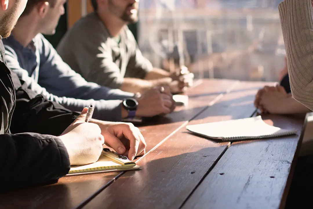 A closeup on the hands of young professionals sitting at a table together.